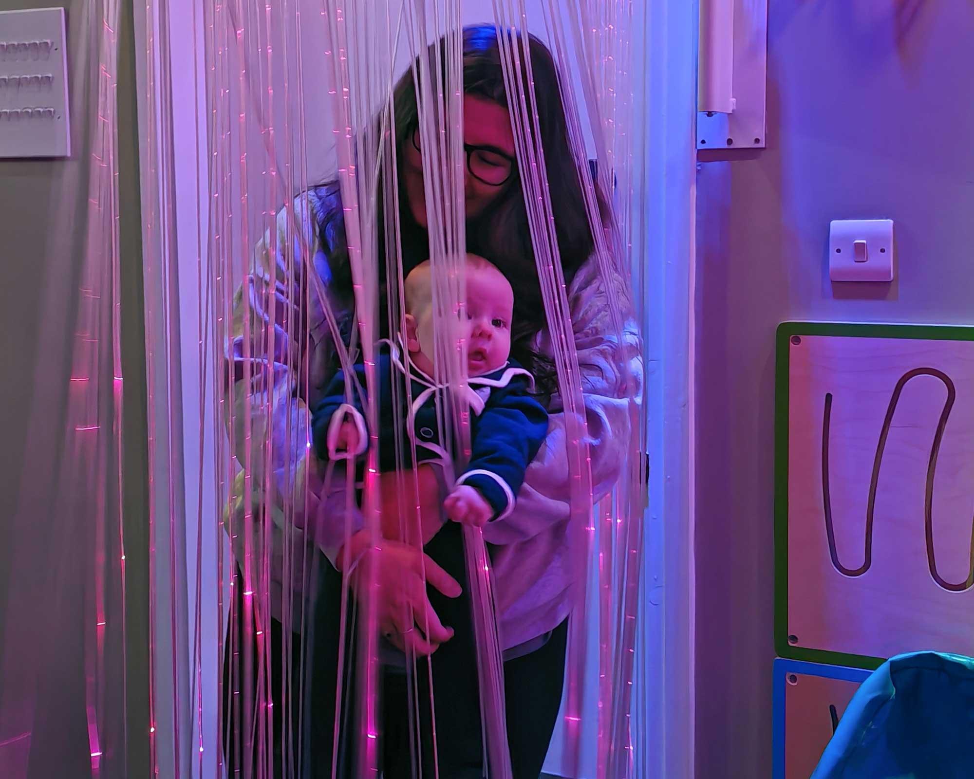 woman holding baby smiling in sensory room at dimensions
