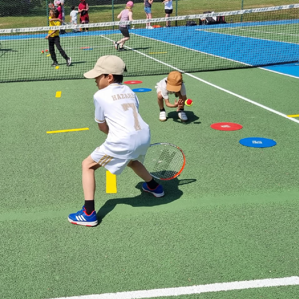 Image shows children playing tennis is the park